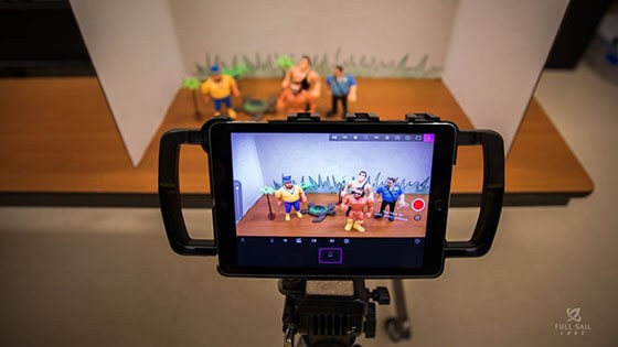 Photographing a scene of figurines in a mini studio.